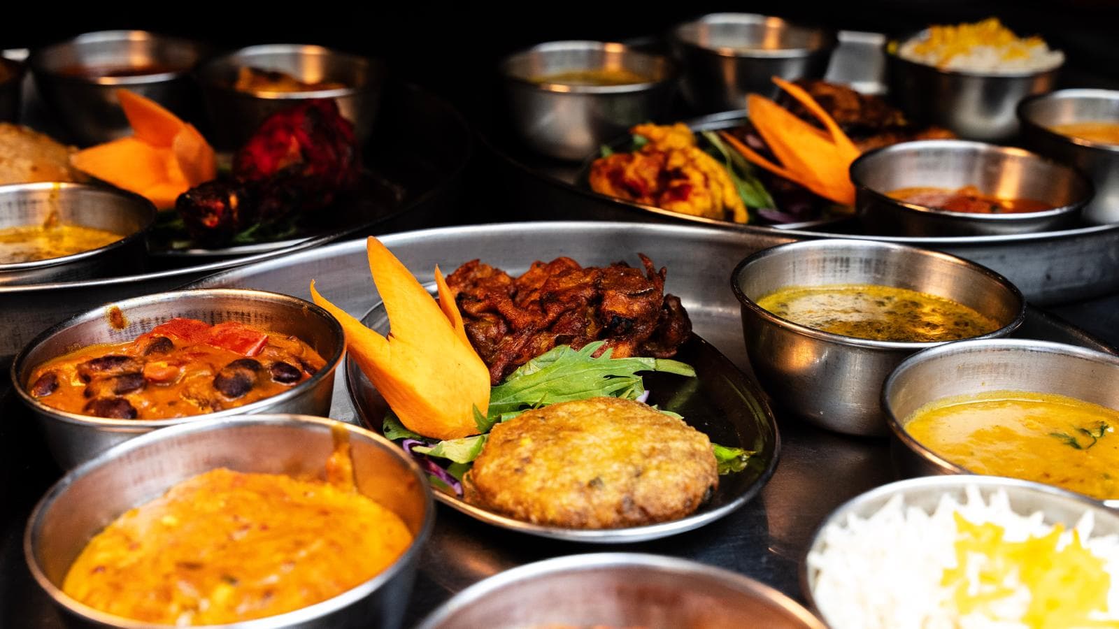 Détail d'un thali : petits bols de currys, dal et riz basmati disposés autour d'un nan