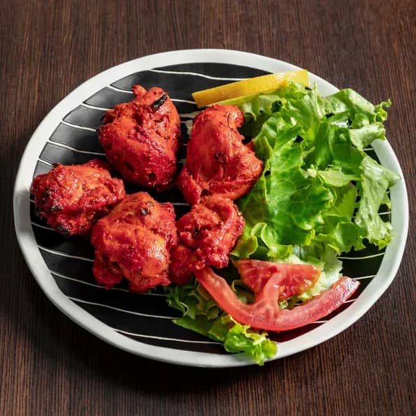 Morceaux de poulet tikka marinés et grillés au tandoor, servis avec salade et citron