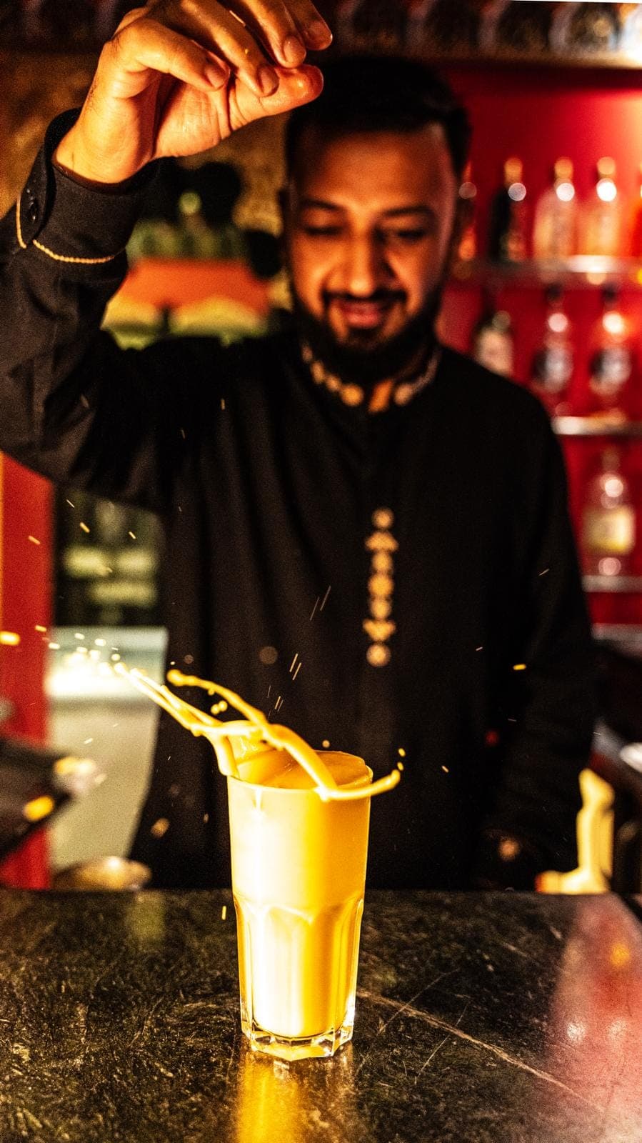 Lassi à la mangue versé dans un verre givré, éclaboussures de lait